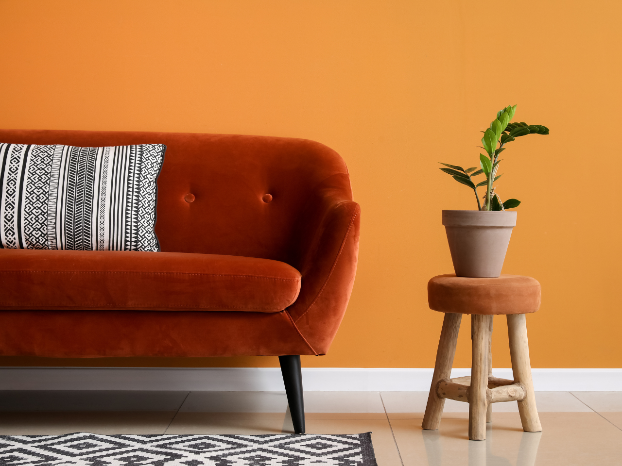 Burnt orange feature wall and velvet sofa, showcasing bold DIY creativity and vibrant colour experimentation for 2025 Paint Trends