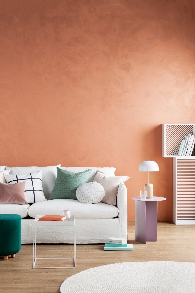 Bright artisan-finish peach wall with colourful cushions and modern decor, showcasing DIY Creativity and 2025 Paint Trends