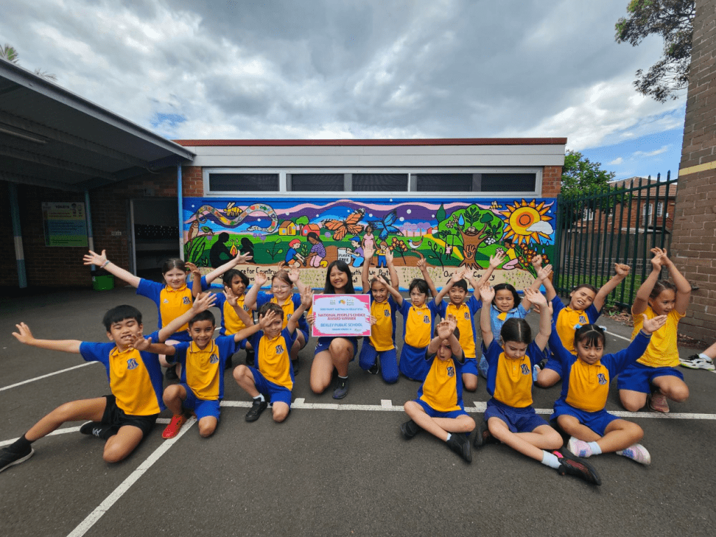 Students celebrating in front of the completed Bexley Public School mural, “Our Living Country”, after winning Paint Australia Beautiful