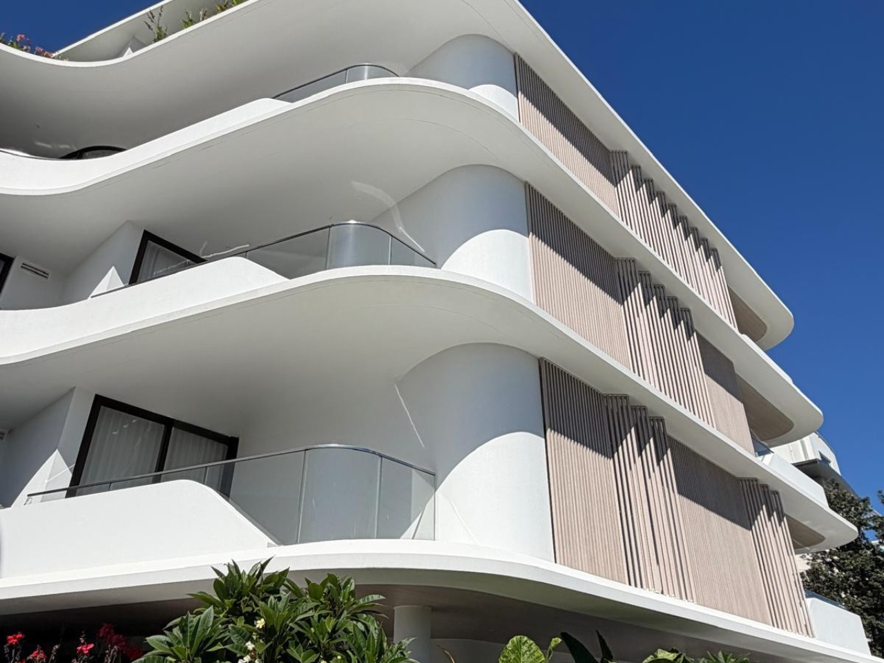 Close-up of the curved rendered façade at Solstice Cronulla showcasing precision rendering and architectural detailing