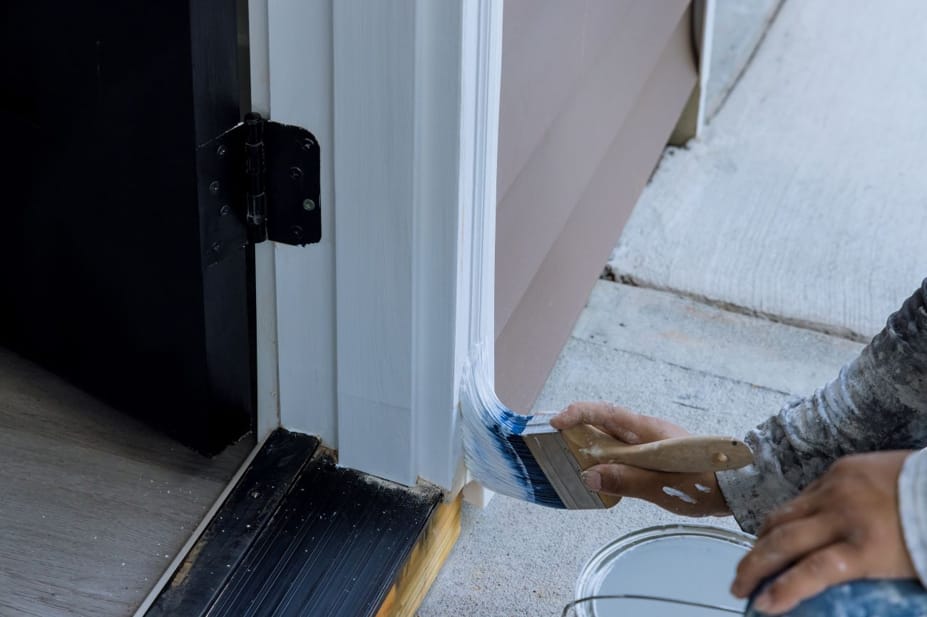 Applying paint to a door frame using a brush for a durable trim finish